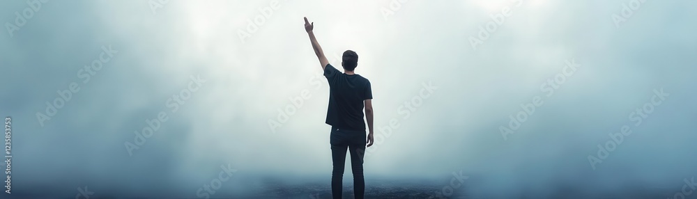 A person standing with raised hand, expressing triumph and resilience against a foggy backdrop, symbolizing hope and determination. People raise arm stand in field. A person standing with raised hand, expressing triumph and resilience against a foggy backdrop, symbolizing hope and determination. People raise arm stand in field.