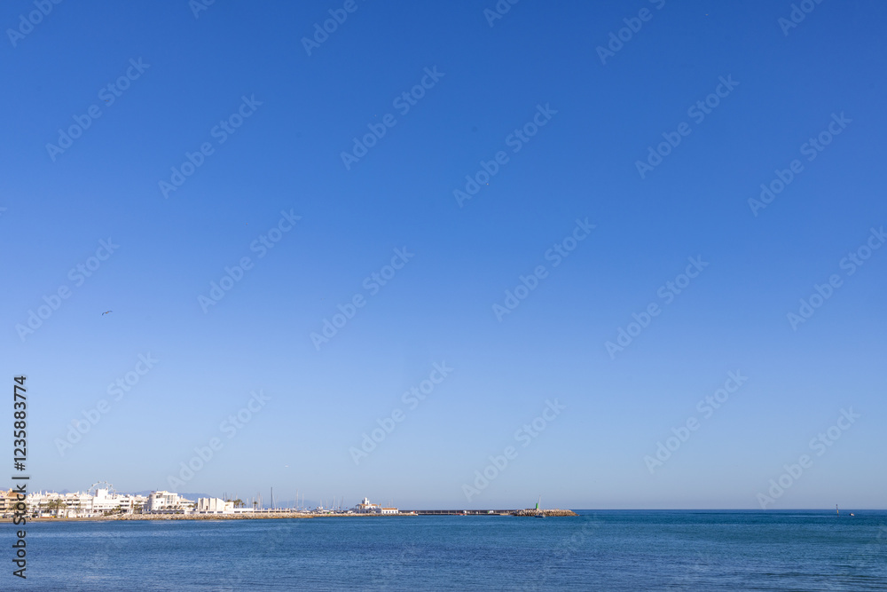 Photo of the beautiful beach front in the Spanish town of Benalmadena in Spain showing the ocean front by the marina on a hot sunny day with nothing but blue skies in the summer time Photo of the beautiful beach front in the Spanish town of Benalmadena in Spain showing the ocean front by the marina on a hot sunny day with nothing but blue skies in the summer time