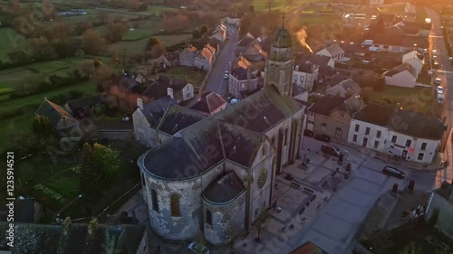 Eglise Saint-Gervais et Saint-Protais, church, Jublains town at sunset, Mayenne in France. Aerial drone top-down orbiting photo