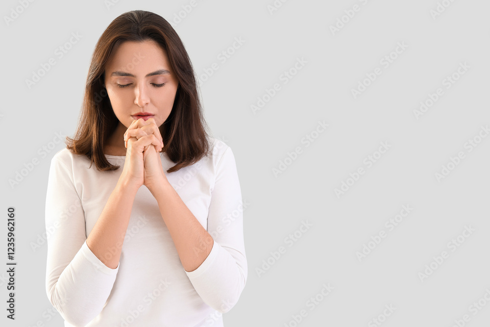 Young woman praying on light background Young woman praying on light background