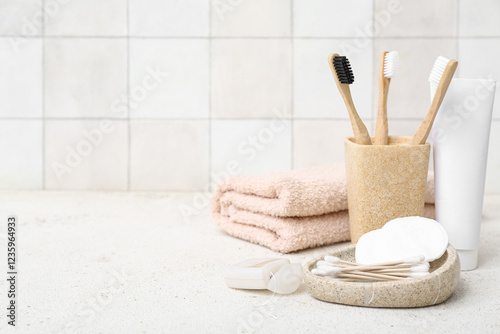 Set of different bath supplies on table against light tile wall photo