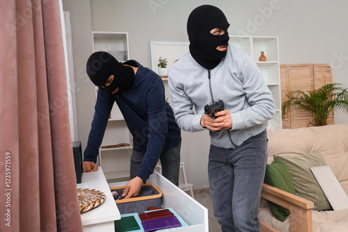 Fotografie Male thieves stealing valuables from open drawer in room