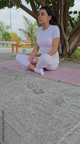 Latina teenager doing yoga under a tree at the park (Bhadrasana Pose) photo