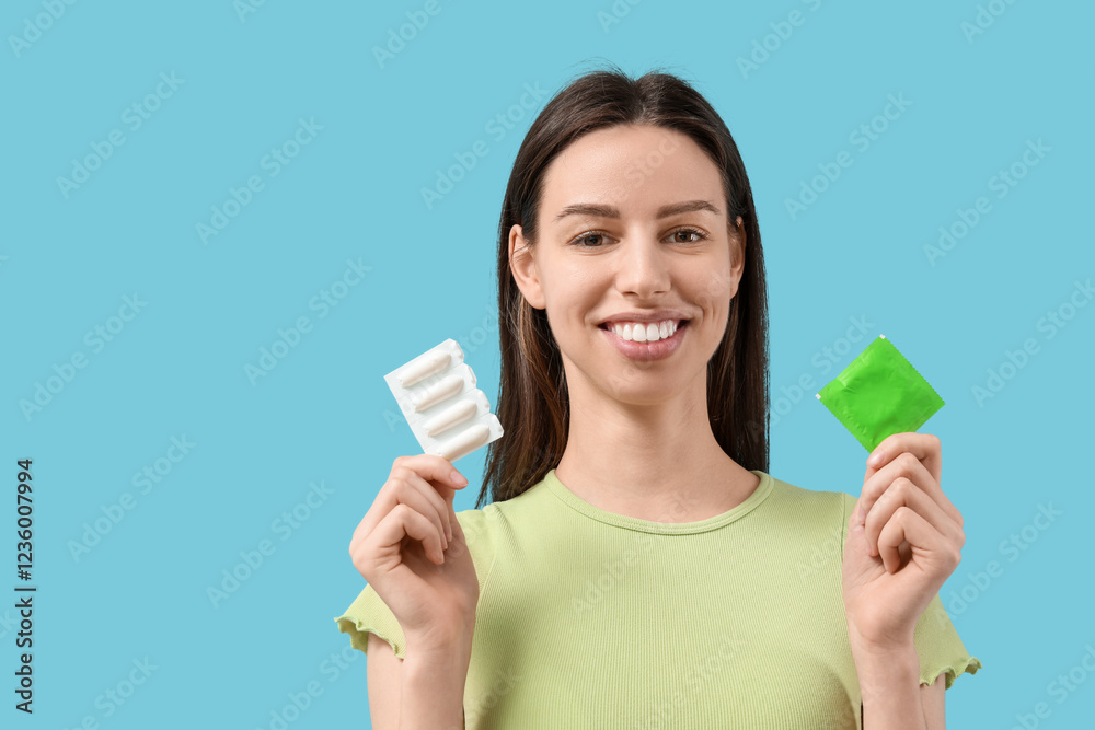 Beautiful young woman with condom and vaginal suppositories on blue background Beautiful young woman with condom and vaginal suppositories on blue background