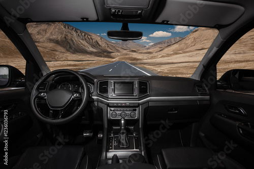 A car is driving down a road with a mountain in the background