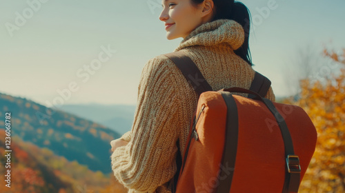 Woman enjoys nature during autumn, wearing a cozy sweater with a backpack while surrounded by colorful foliage photo