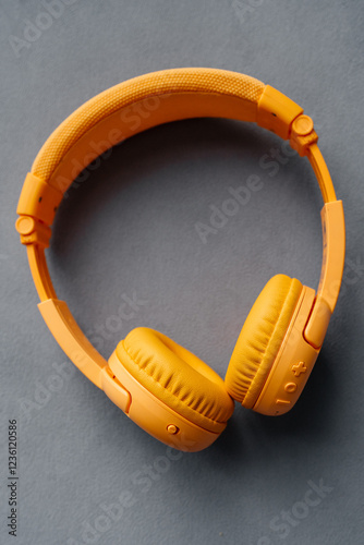 Children's wireless headphones yellow on a gray background. Music and technology.