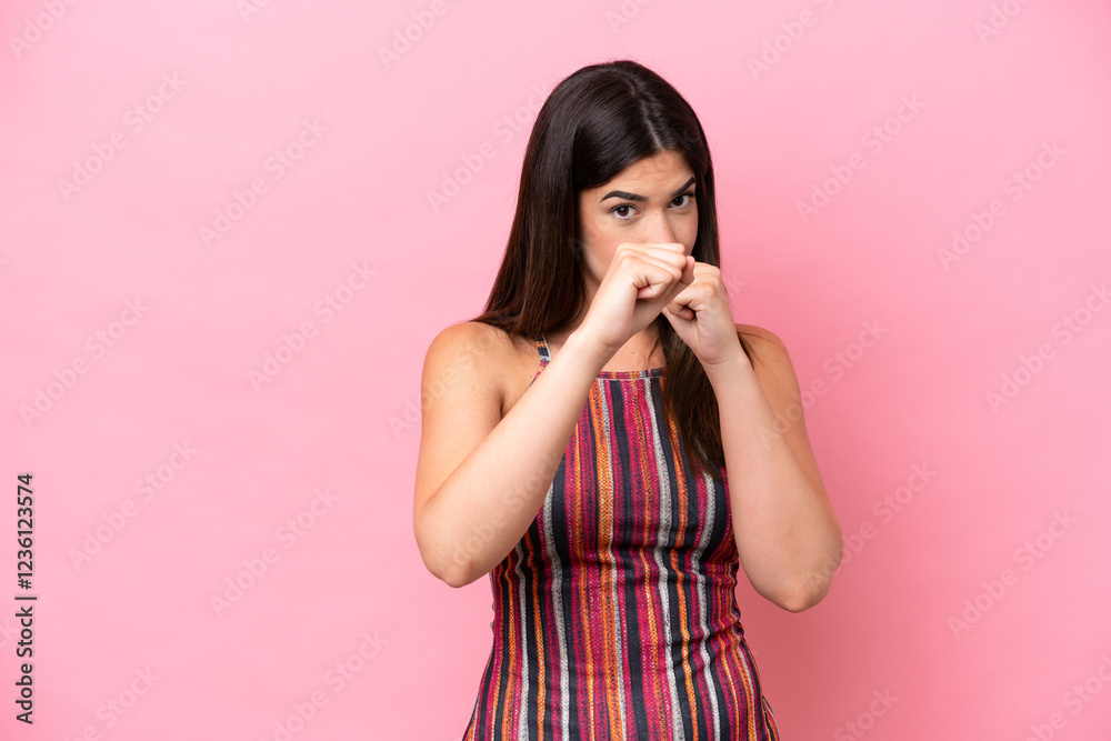 Young Brazilian woman isolated on pink background with fighting gesture Young Brazilian woman isolated on pink background with fighting gesture