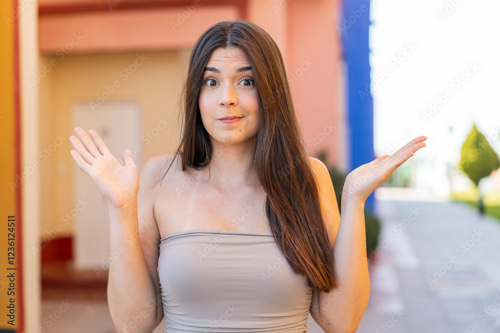 Young pretty Brazilian woman at outdoors making doubts gesture Young pretty Brazilian woman at outdoors making doubts gesture