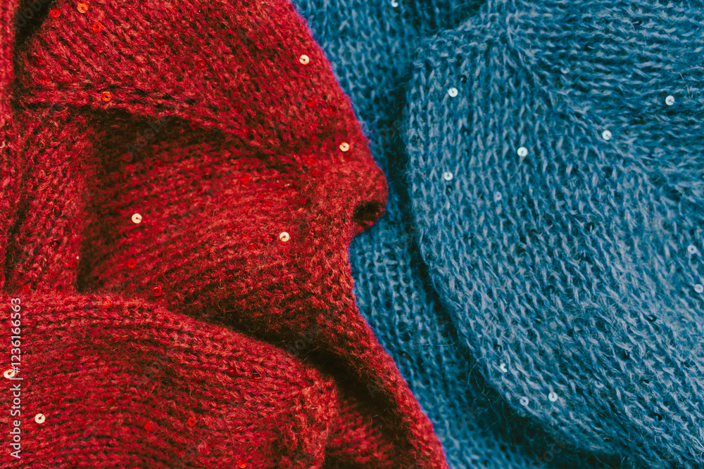 Red and blue knitted sweater with sequins. Sequinned knitwear. Sequin pattern in needlework. Knitting hobby. Knitter work. Sequins texture in knitwear. Bright knitted fashion for holidays.