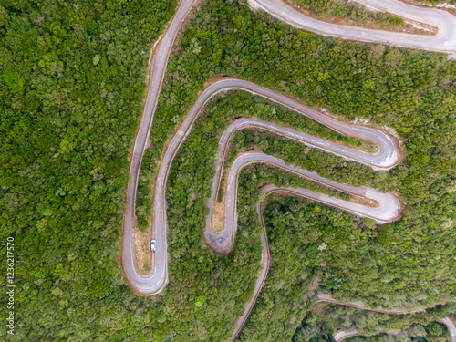 Winding mountain road seen from above, a single vehicle navigating the curves. photo