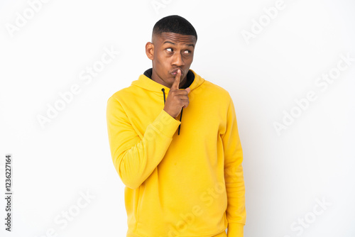 Young latin man isolated on white background showing a sign of silence gesture putting finger in mouth photo