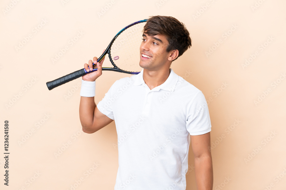 Young caucasian man isolated on ocher background playing tennis and looking up Young caucasian man isolated on ocher background playing tennis and looking up