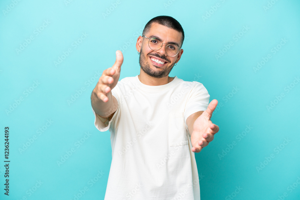 Young caucasian man isolated on blue background presenting and inviting to come with hand Young caucasian man isolated on blue background presenting and inviting to come with hand