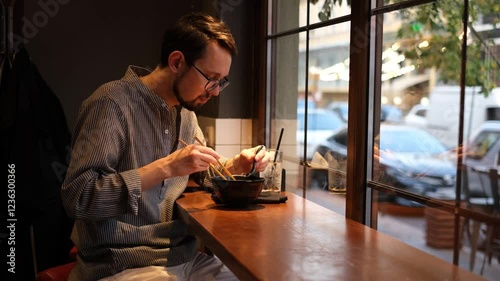portrait of a young man with a beard eating ramen in a Japanese restaurant