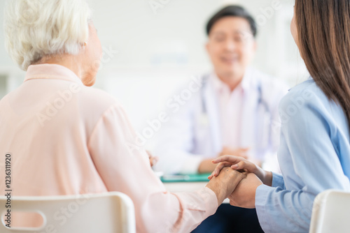 Focus at woman hold her mum hand to give encouragement while see doctor at hospital blur doctor ground. photo