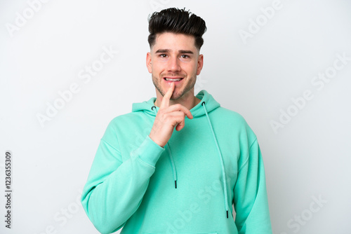 Young caucasian man isolated on white background showing a sign of silence gesture putting finger in mouth photo