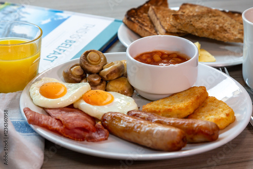 Full Irish breakfast served at a hotel with sausge, eggs, baked beans, bacon, hash browns and mushrooms.