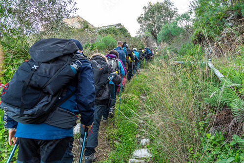 Coda di trekker su percorso di campagna visti di spalle photo