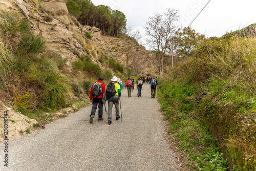 Escursionisti camminano su strada in campagna visti di spalle photo