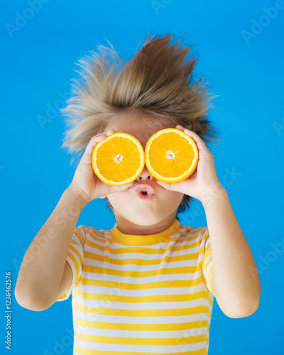 Funny kid with his hair standing on end. Surprised child holding slices of orange