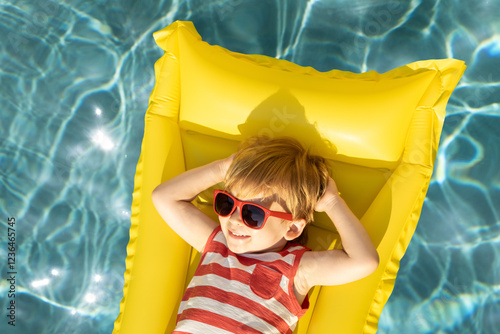 Happy child having fun on summer vacation. Funny kid playing in swimming pool.