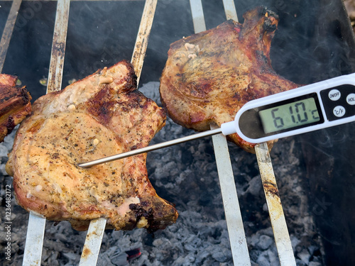 two pieces of meat grilling, with thermometer reading 61.0 C. Meat appears browned and appetizing.