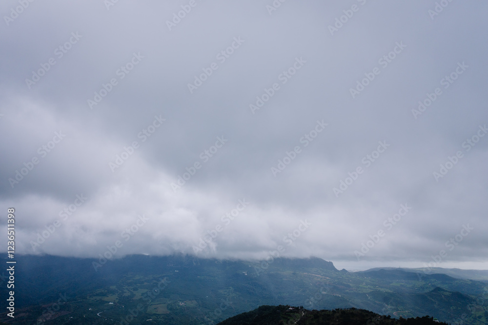 Aerial view of mist-covered mountains and valleys under a dramatic overcast sky, creating a serene and atmospheric rural landscape. Aerial view of mist-covered mountains and valleys under a dramatic overcast sky, creating a serene and atmospheric rural landscape.