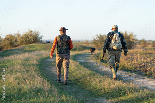 Mature hunter man holding a shotgun and walking through a field photo