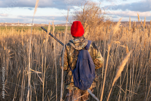 Mature hunter man holding a shotgun and walking through a field photo