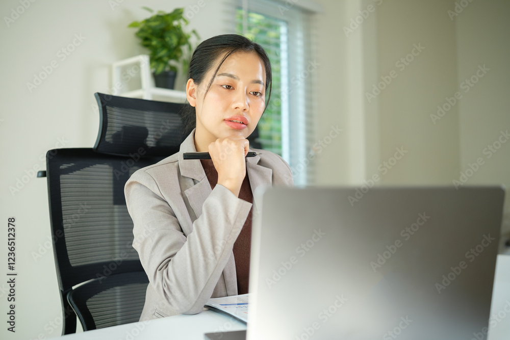 Thoughtful professional businesswoman sitting at her desk and analyzing details on her laptop. Thoughtful professional businesswoman sitting at her desk and analyzing details on her laptop.