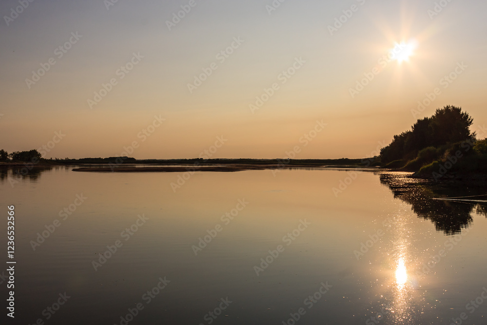 Obraz premium A calm lake with a sun reflecting on the water