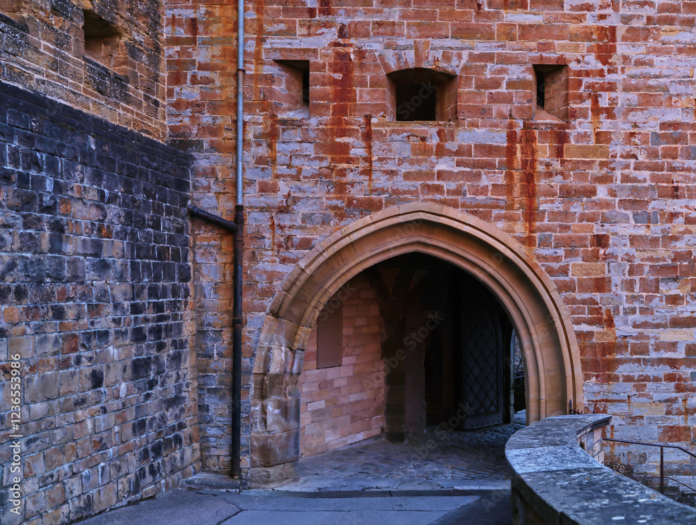 The image showcases a beautifully textured archway from a historic castle, framed by rugged stone walls that exhibit rich history and architectural elegance. The image showcases a beautifully textured archway from a historic castle, framed by rugged stone walls that exhibit rich history and architectural elegance.