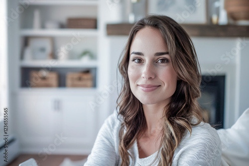 Close-up portrait of a confident young woman in a bright  modern living room with shelves and cozy decor in the background
