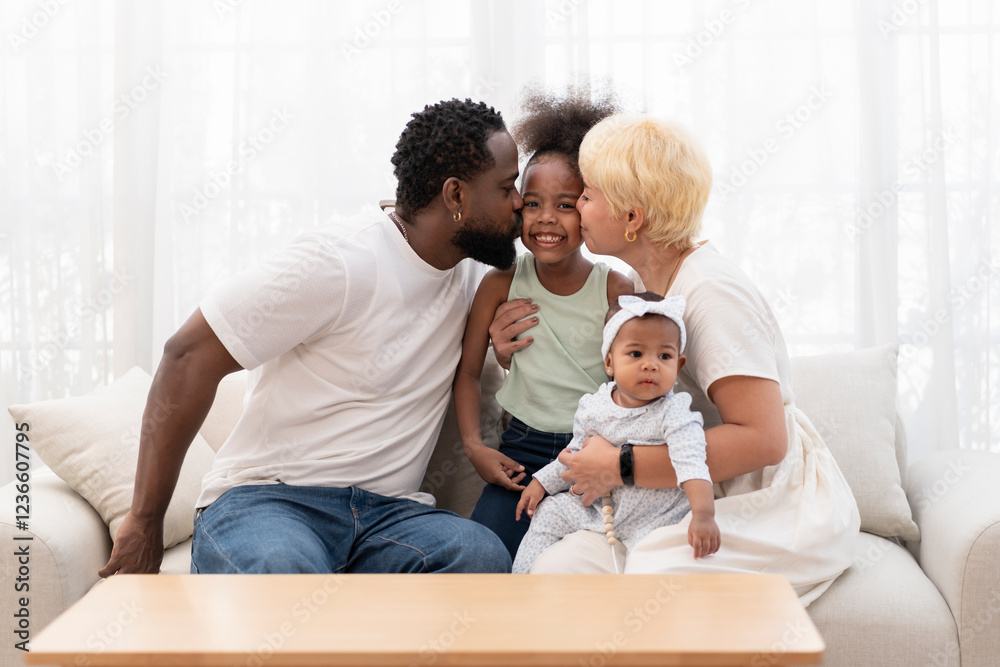 Fototapeta premium bonding black family spend free time together in the living room,father and mother embracing a daughter and kiss on cheek with affectionate