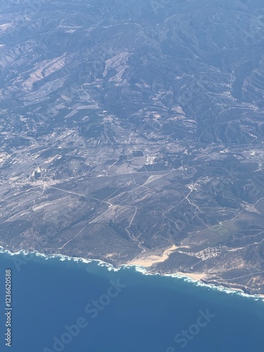 Aerial view from an airplane window with views of dramatic coastline. 