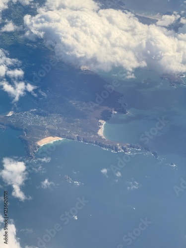 Aerial views form a plane looking through the clouds onto dramatic coastline. 