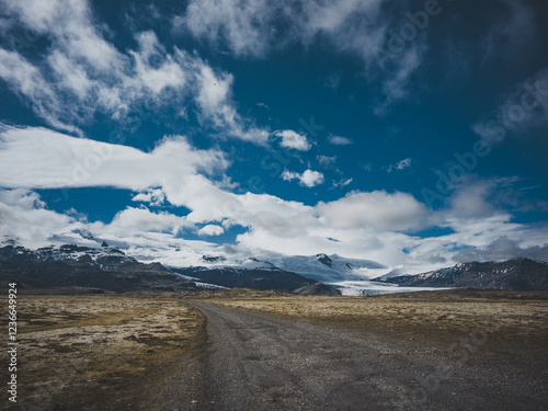 Route isolée menant à un glacier sous un ciel dramatique en Islande