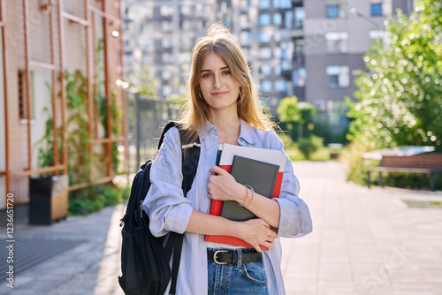 Portrait of young college student, girl with backpack textbook, outdoors