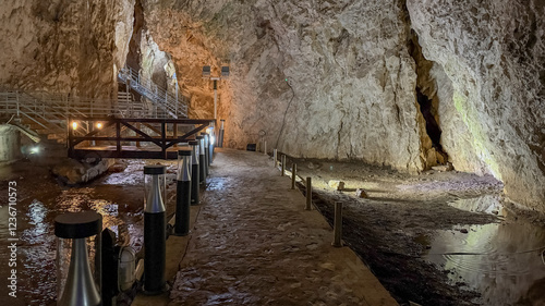 Illuminated limestone cave interior with wooden walkway, representing adventure and exploration, ideal for nature tourism and environmental conservation concepts  stopica pecina photo