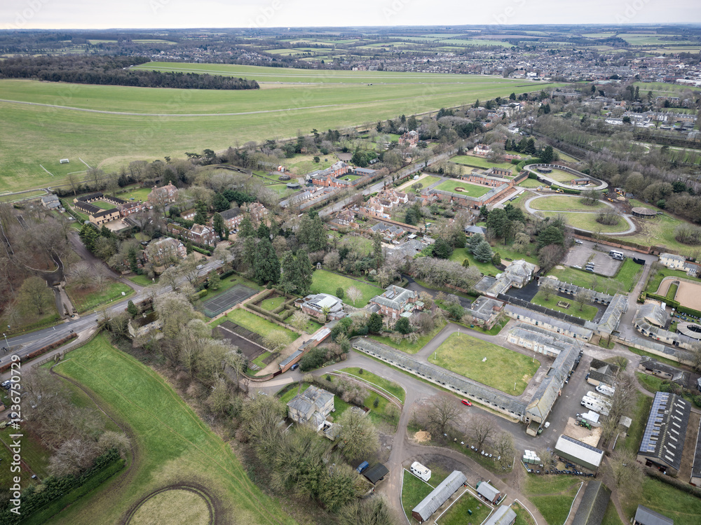 Fototapeta premium Aerial view of horse racing stables and therapy buildings seen nestled between large private houses in the famous horse racing town of Newmarket, Suffolk, UK. Seen at the edge of the famous Gallops.