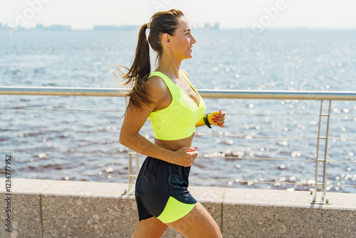 Canvas-taulu Woman jogs along waterfront path during daytime enjoying fitness and exercise