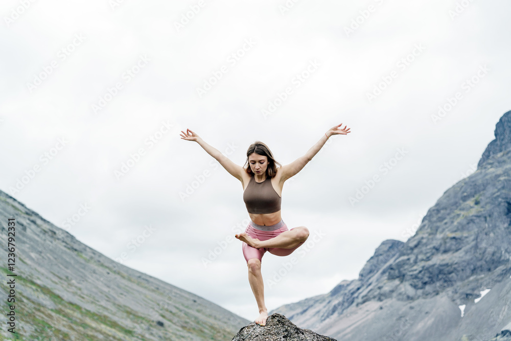 Woman practicing yoga in a mountain landscape during cloudy weather Woman practicing yoga in a mountain landscape during cloudy weather