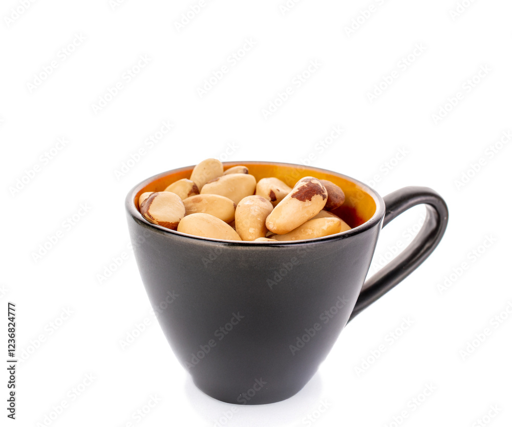 Brazil nuts without shells in a black ceramic cup, macro, isolated on white background. Brazil nuts without shells in a black ceramic cup, macro, isolated on white background.