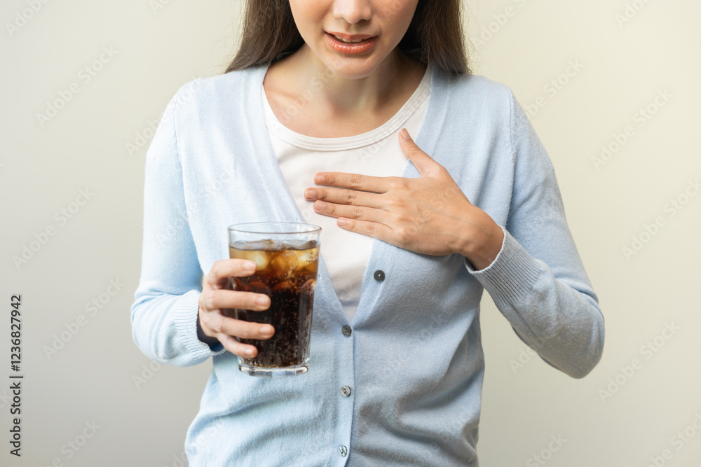 Acid reflux disease, suffer asian young woman, girl hand holding a glass of cola, have symptom gastroesophageal, heartburn pain on chest when drinking sparkling, soft water. Healthcare medical concept Acid reflux disease, suffer asian young woman, girl hand holding a glass of cola, have symptom gastroesophageal, heartburn pain on chest when drinking sparkling, soft water. Healthcare medical concept