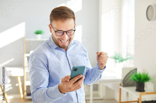 Happy man celebrating victory or good news at home, exclaiming 