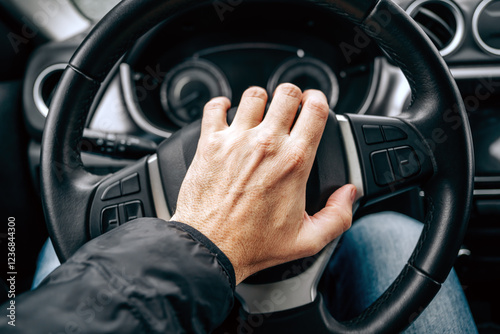 Honking car horn, male hand on a car steering wheel on cold winter day photo