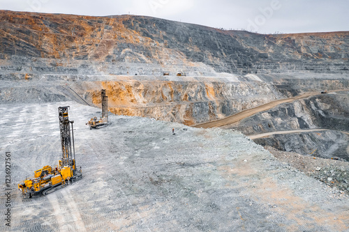 Open pit mine industry, aerial view. Engineers check drill holes for blasting operations. Big yellow mining truck for coal working in quarry photo