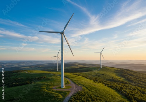 White wind turbines on a green hill under a clear blue sky photo