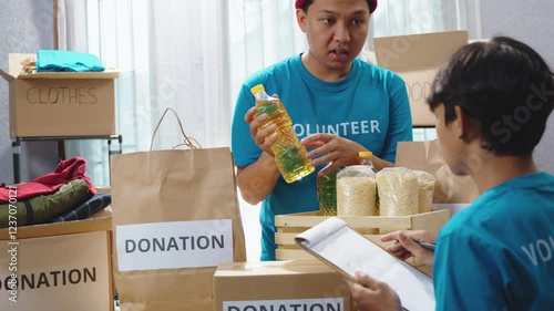 Teen volunteers conducting inventory of donated items at a charity center. Carefully sorting food and clothing before packing them into donation boxes. Donation process, volunteer work, social support